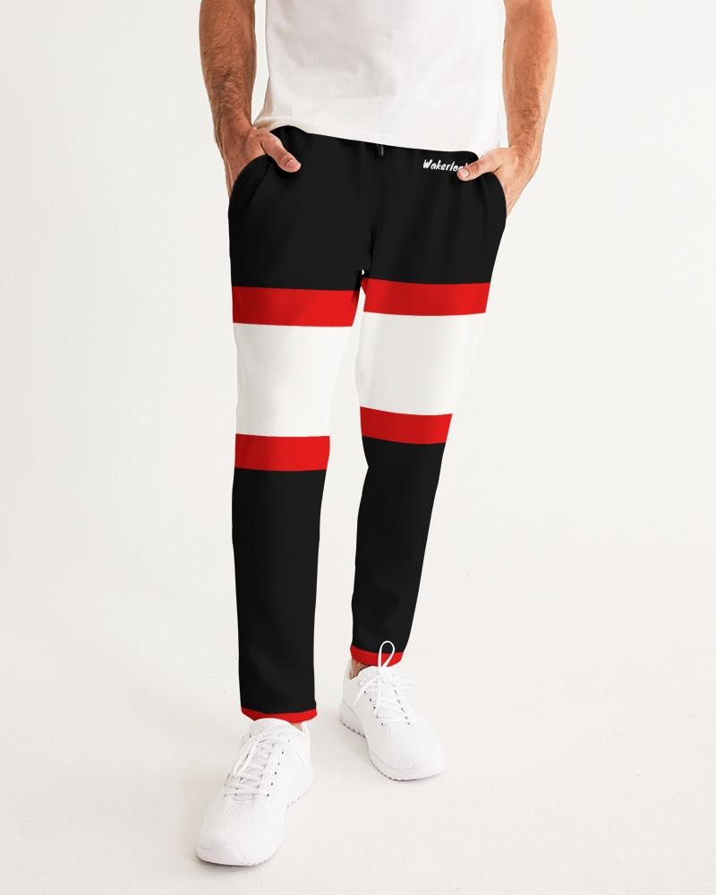 Man wears black pants with red and white stripes and white shoes. White shirt partially visible.