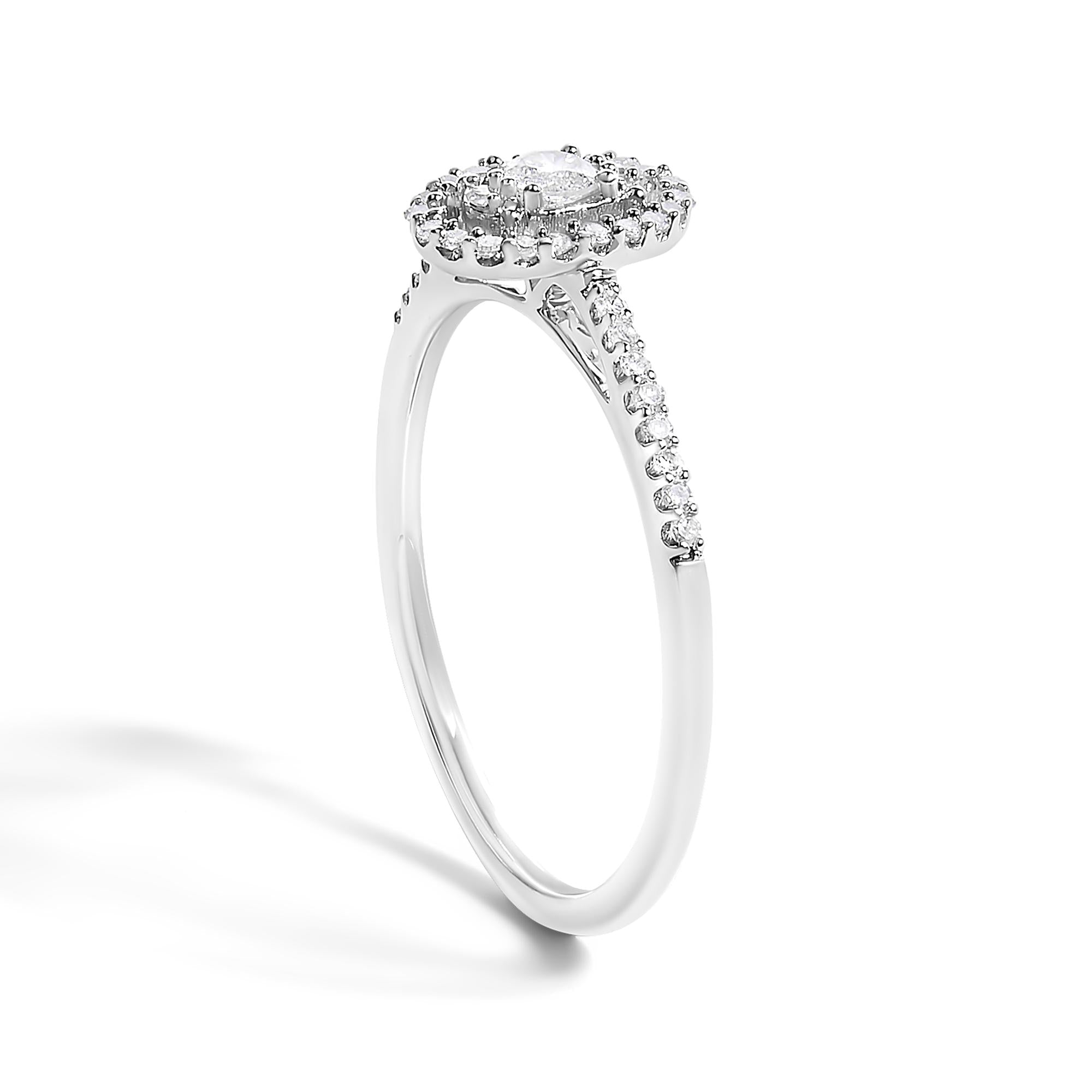 Silver ring with a round diamond halo setting and small diamonds on a slender band.