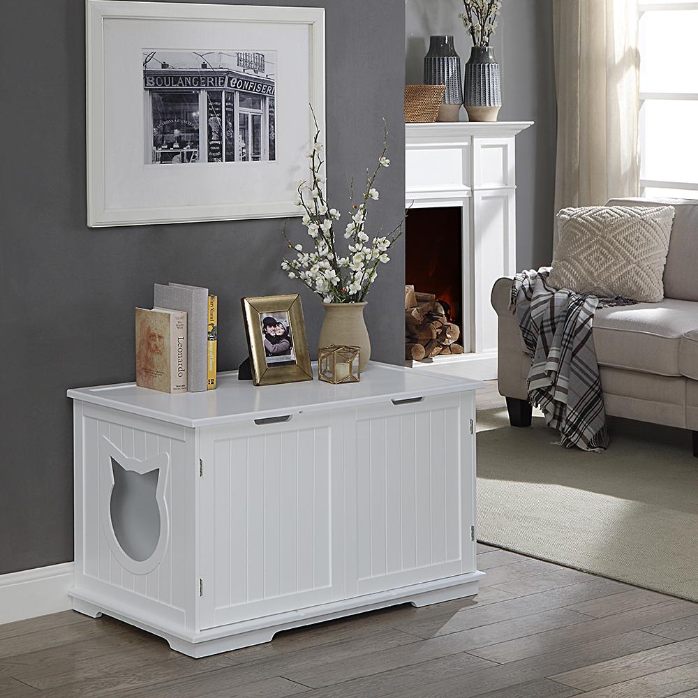 White chest with cat silhouette cutout, surrounded by books, photo frames, flowers, and a sofa.