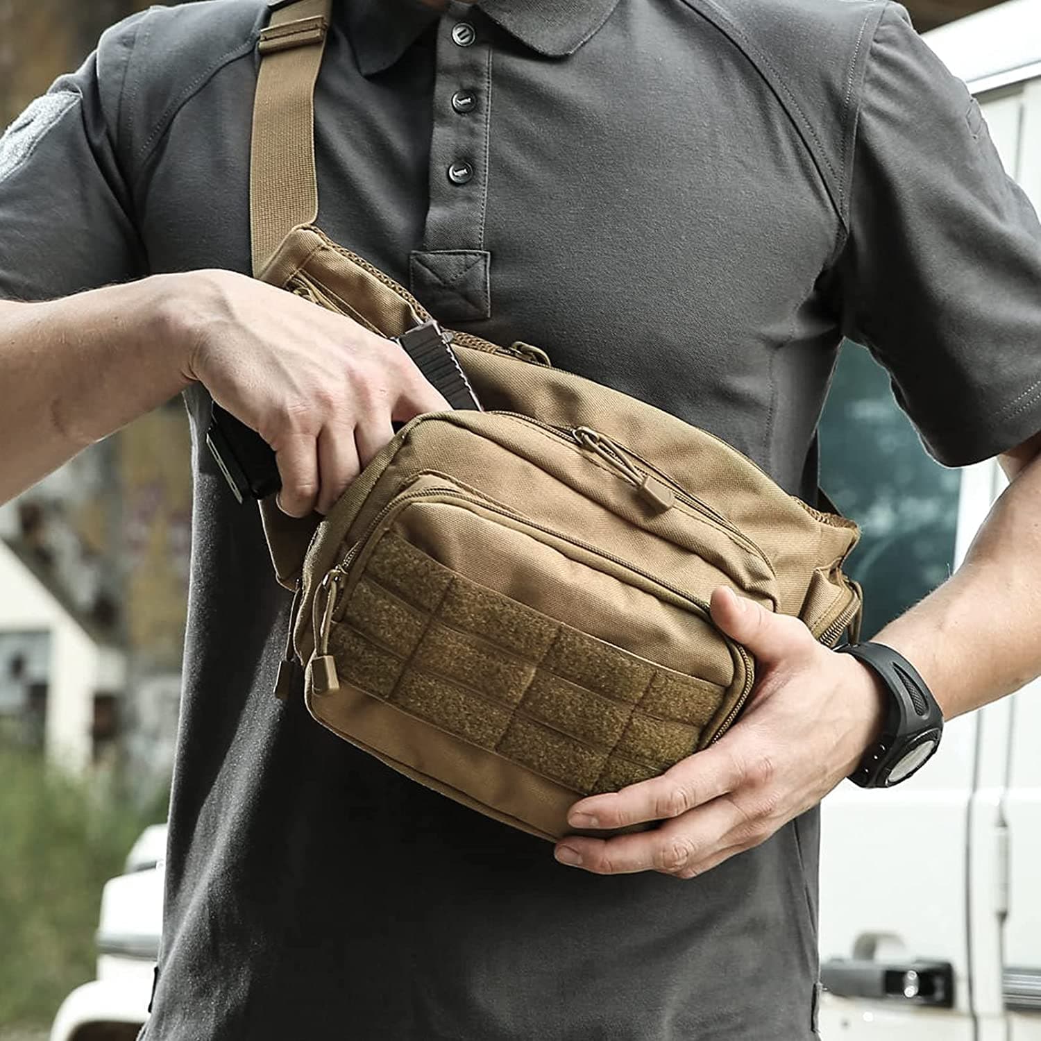 Man with gray shirt accessing a tan tactical sling bag, holding an object by a white vehicle.