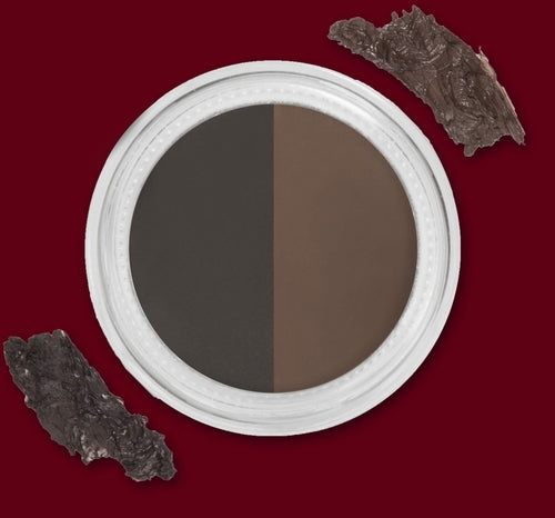 A two-tone brown and black eyeshadow in a white round case, with dark textured pieces nearby.