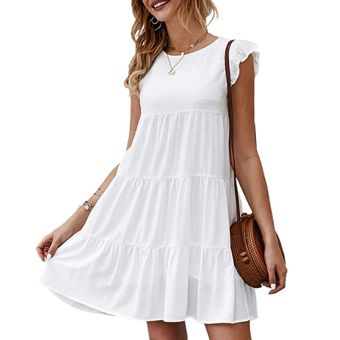 Woman in a white, ruffled dress, holding a round wicker bag; wearing gold jewelry.
