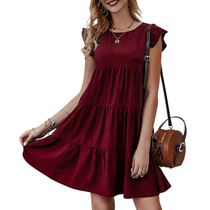 Woman in a red tiered dress with short ruffled sleeves, holding a brown woven handbag.