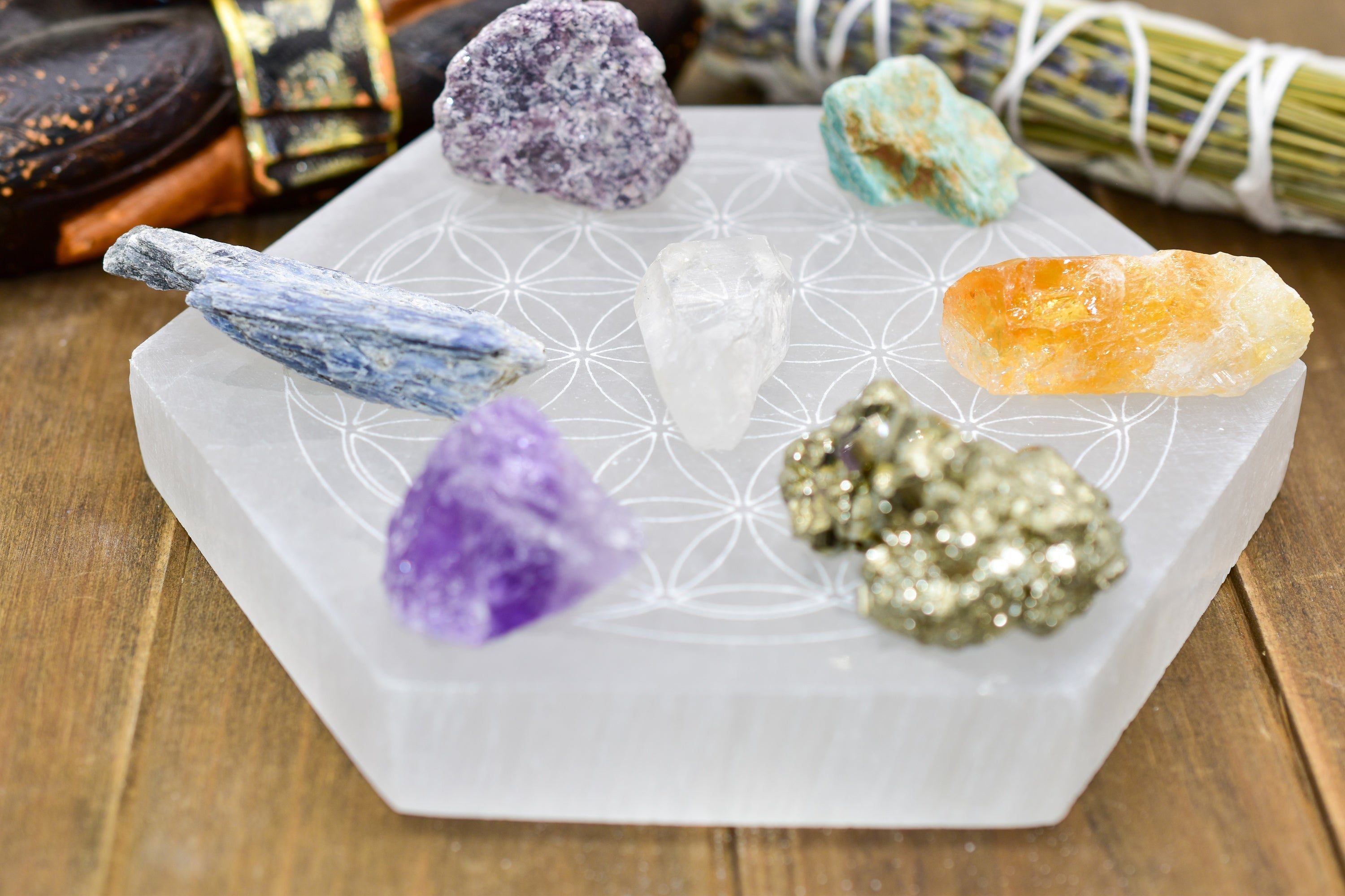 Crystals of various colors on a hexagonal white plate with a floral pattern, atop a wooden surface.