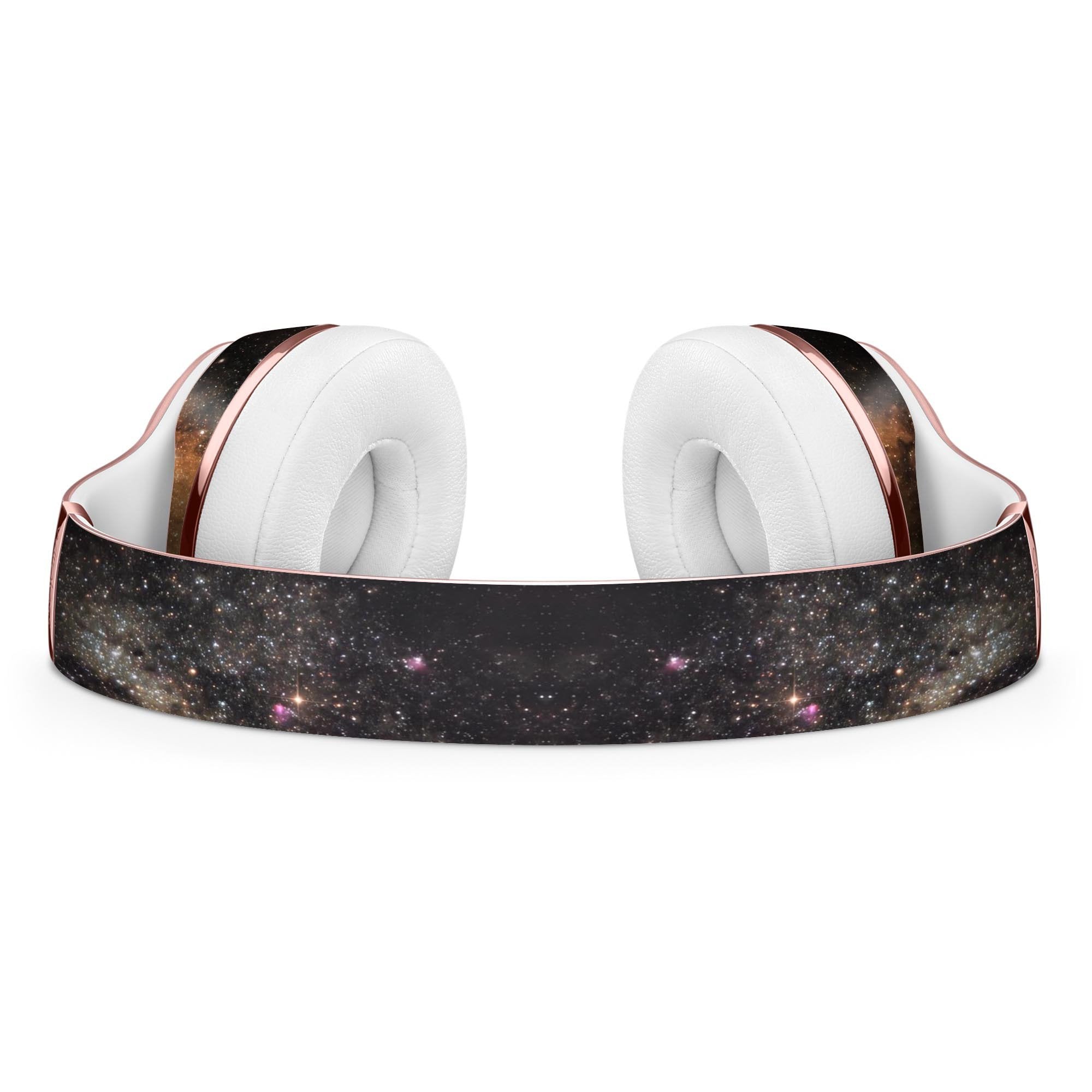 Rose gold headphones with white cushions and starry galaxy print on the headband.