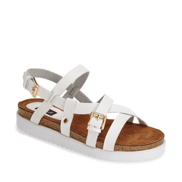 White strappy sandal with gold buckles, brown footbed, and white ridged sole.
