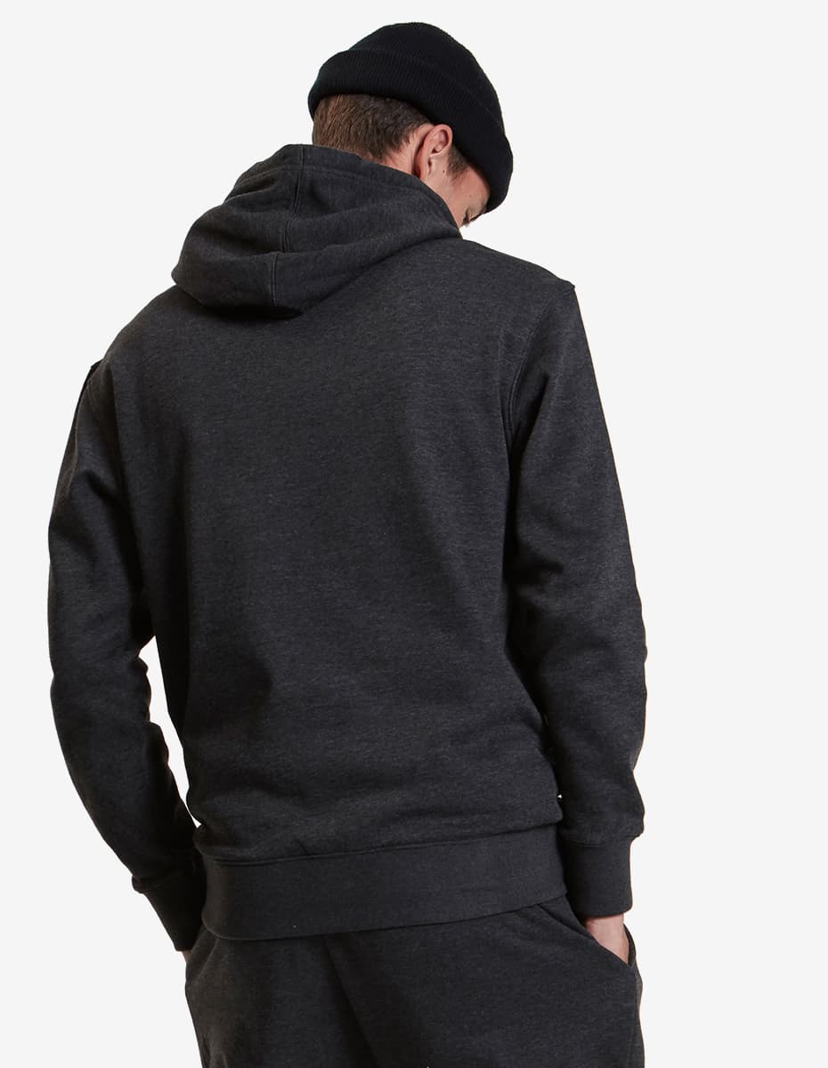 Man in dark hoodie and beanie, facing away with hands in pockets, against white background.