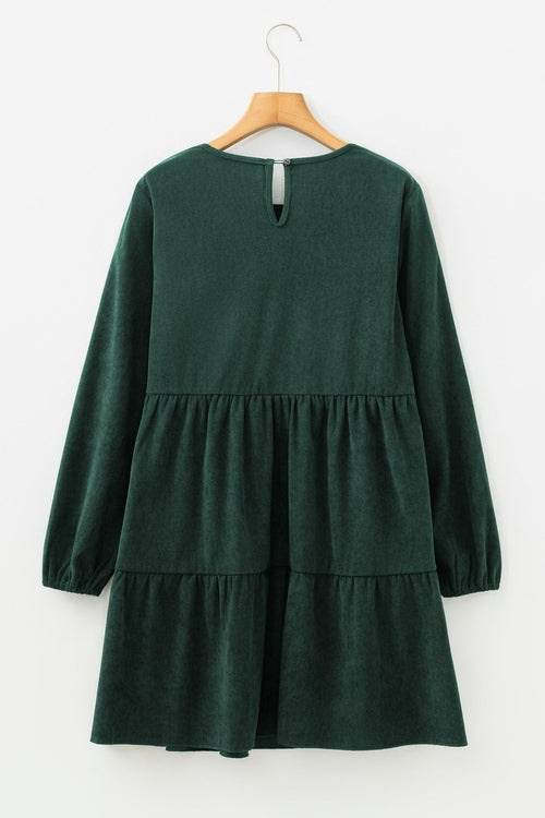 Dark green long-sleeve dress with tiered skirt and keyhole back, hung on a wooden hanger.