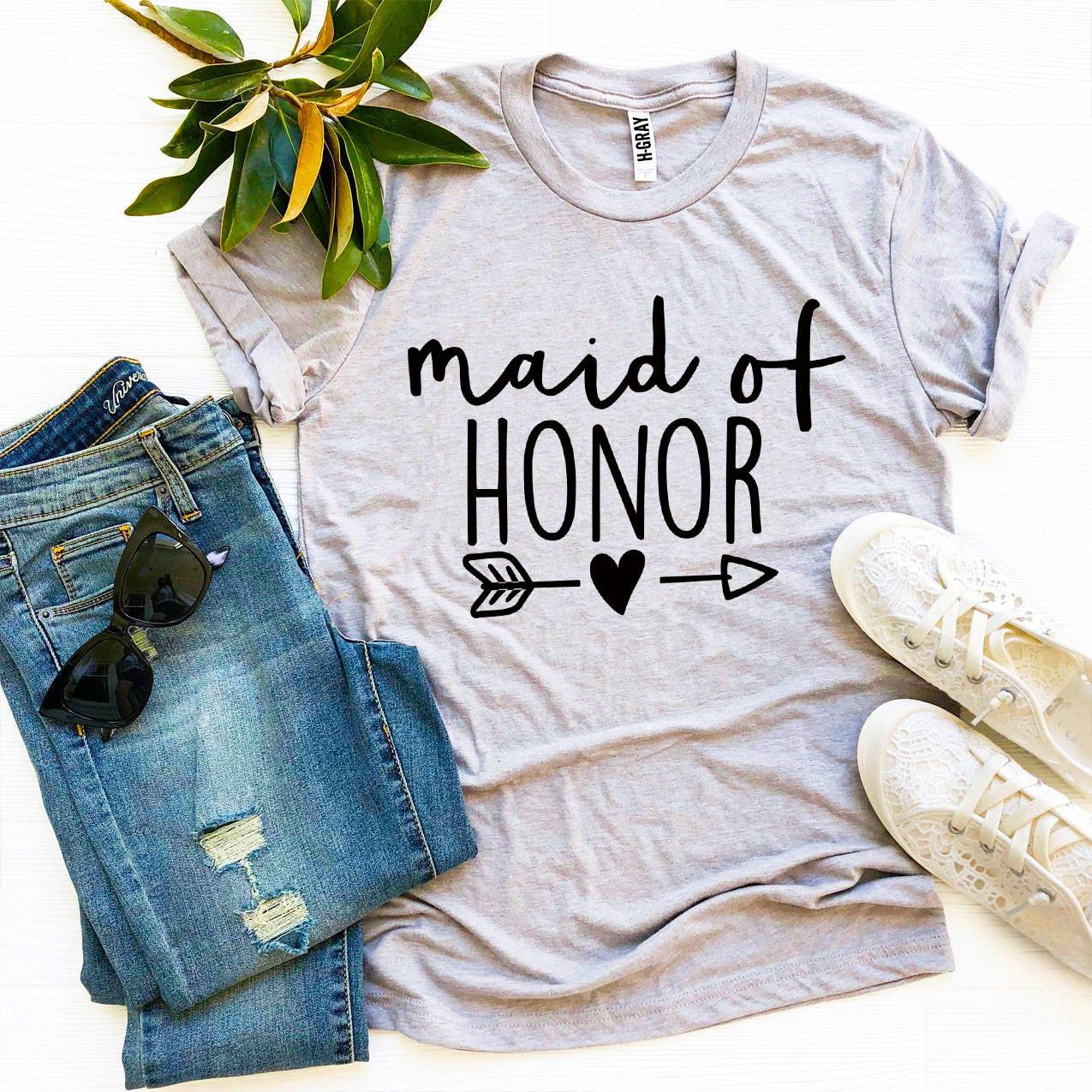 Gray "maid of honor" t-shirt with jeans, sunglasses, white lace sneakers, and green leaves.