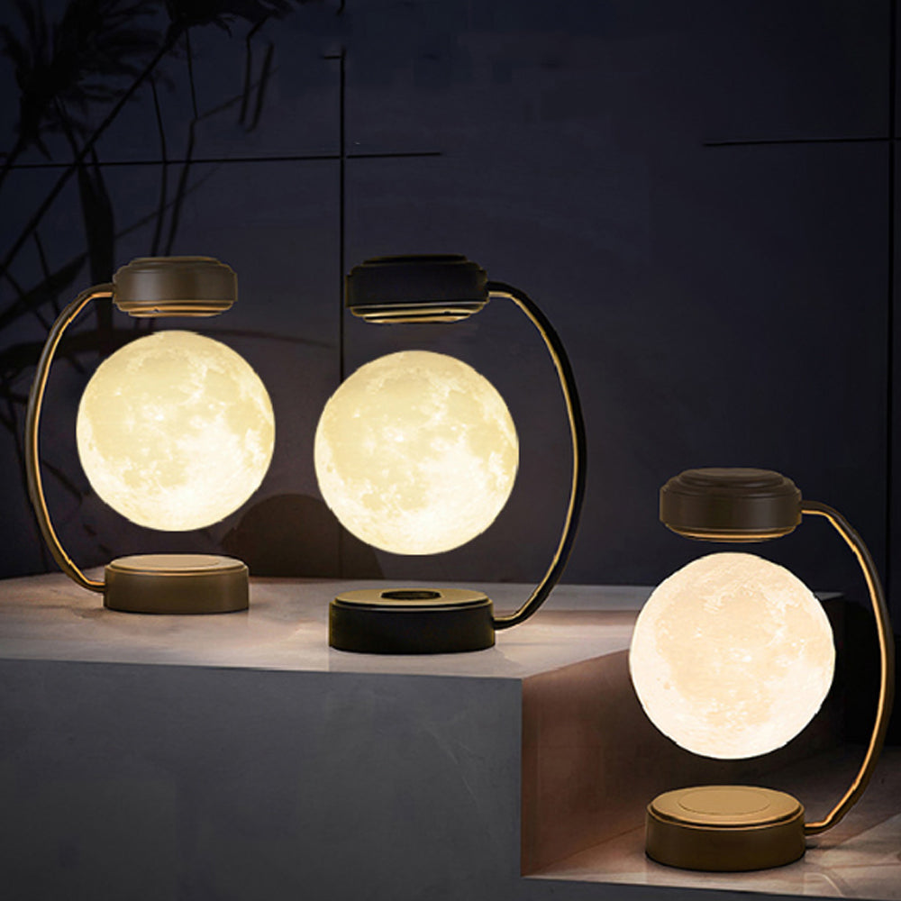 Three levitating moon lamps glow warmly on a dark backdrop, each with a curved metallic stand.