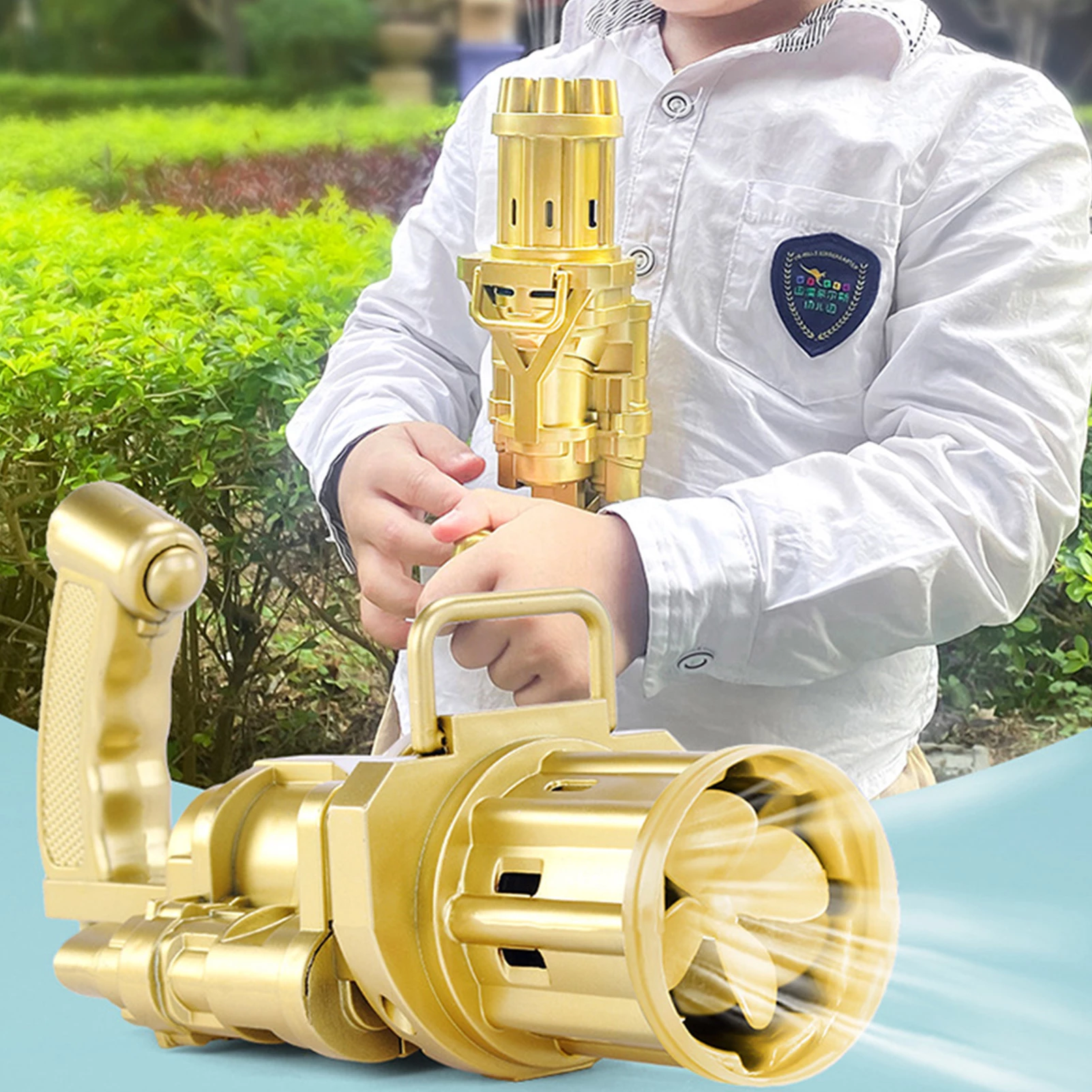 Child in a white shirt holding a gold toy fan gun, with green bushes in the background.