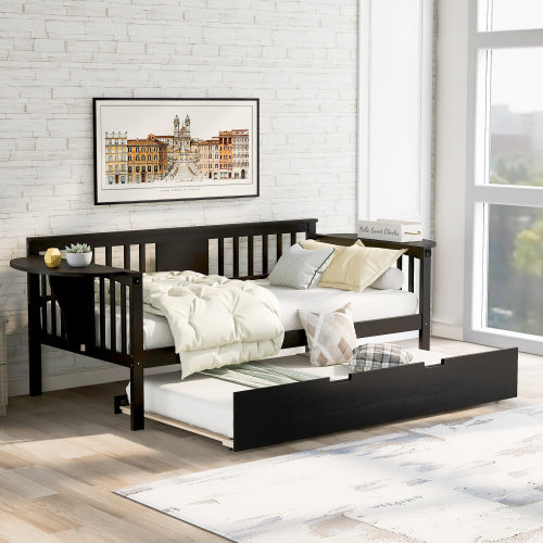 Black daybed with trundle, beige bedding, brick wall, framed art, and sunlight by a large window.