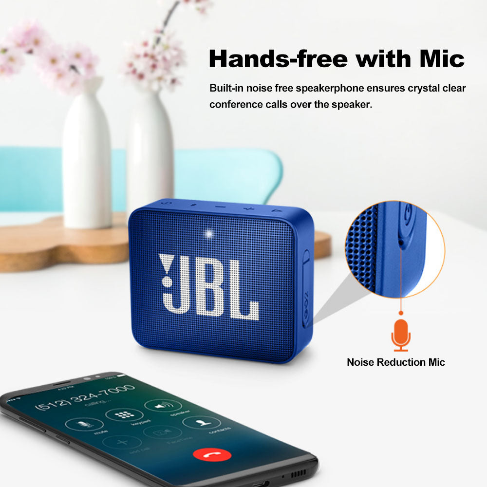 Blue JBL speaker with mic feature; phone showing call screen. Background: flowers and wooden decor.