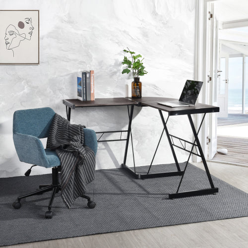 L-shaped desk with laptop, books, and plant; blue chair with gray blanket on gray rug.