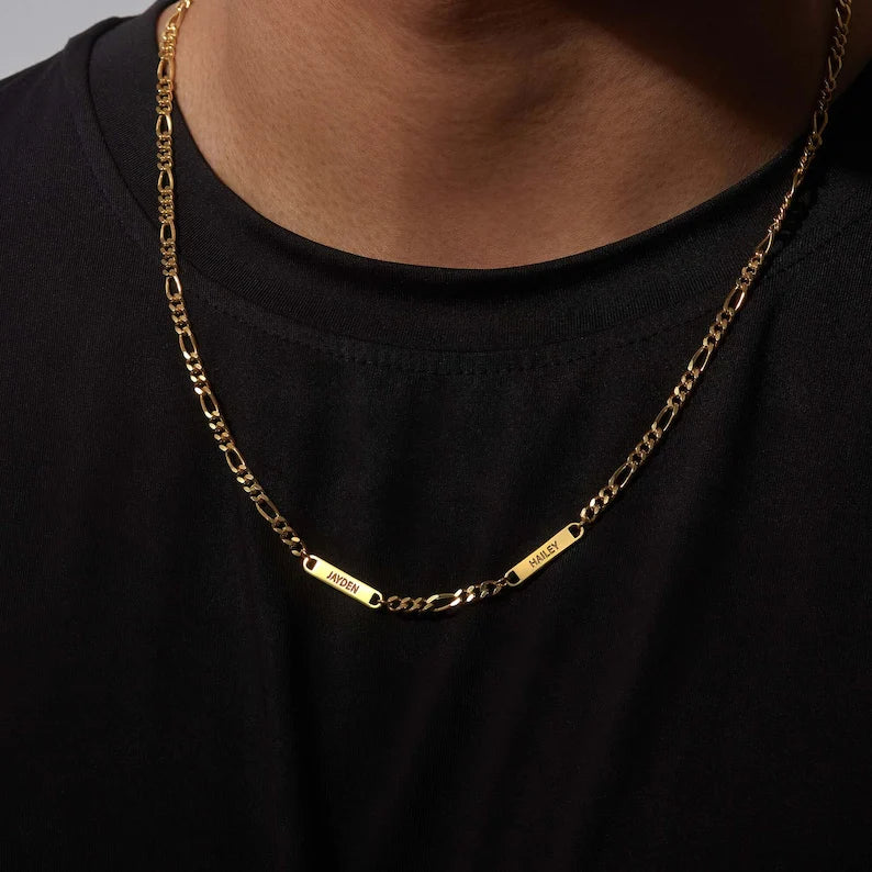 Gold chain necklace with name plates on a person wearing a black shirt.