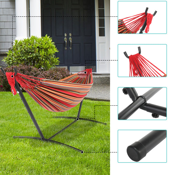 Striped hammock in garden, red and orange, with a black metal stand in front of a house entrance.