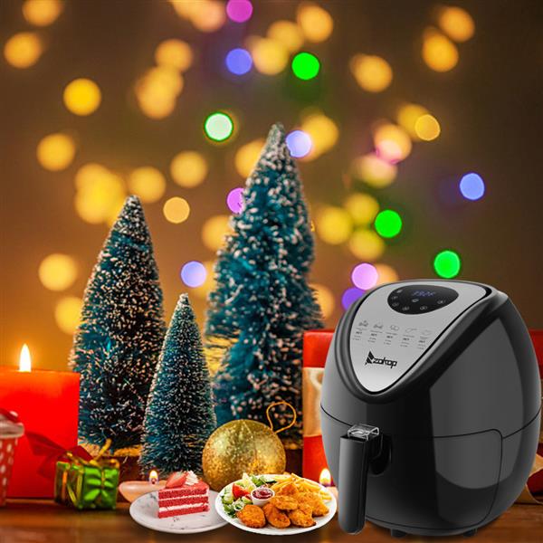 Black air fryer with Christmas lights, small trees, candles, and festive food in the foreground.