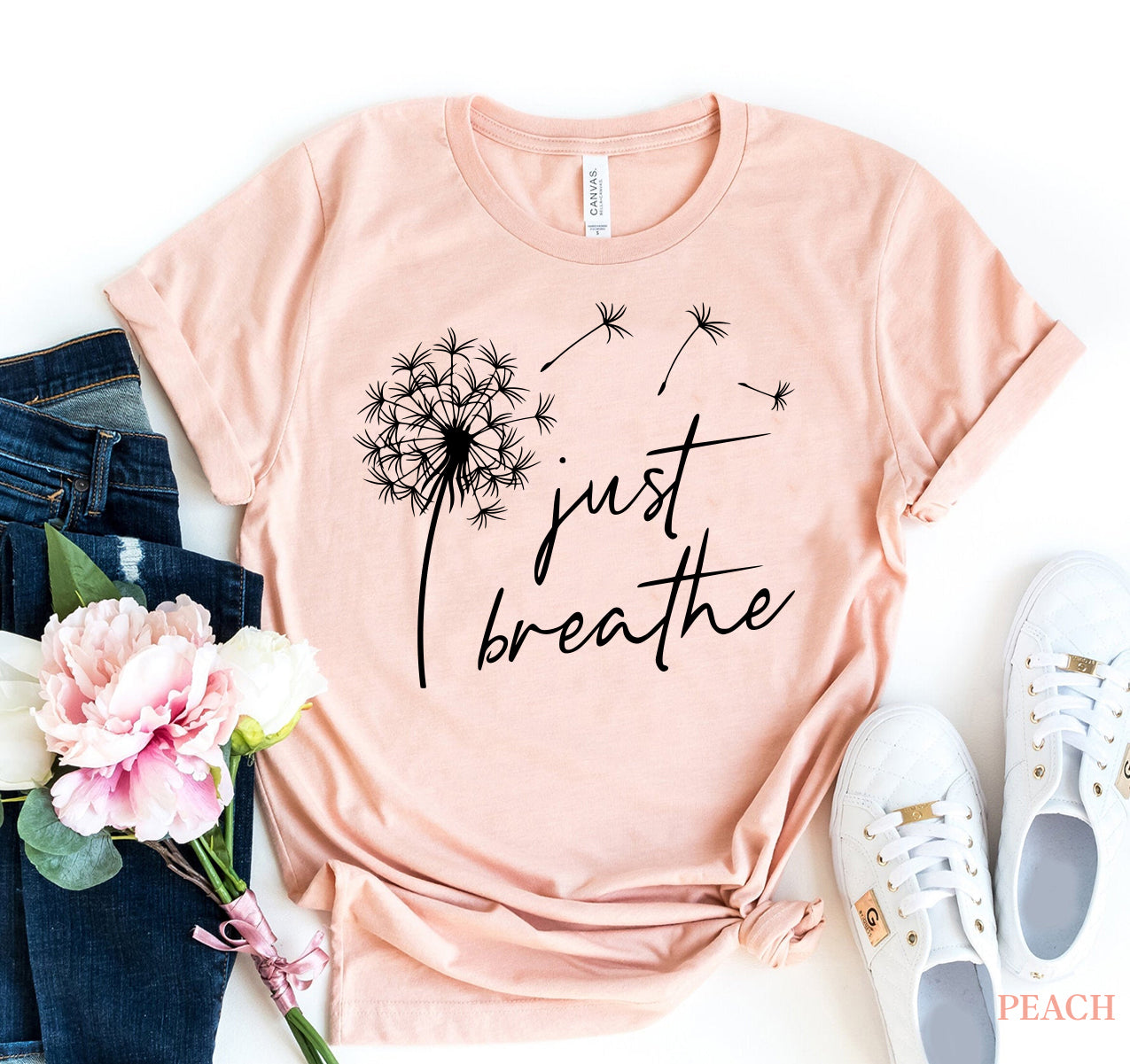 Peach shirt with “just breathe” text and dandelion, paired with jeans, white shoes, and flowers.