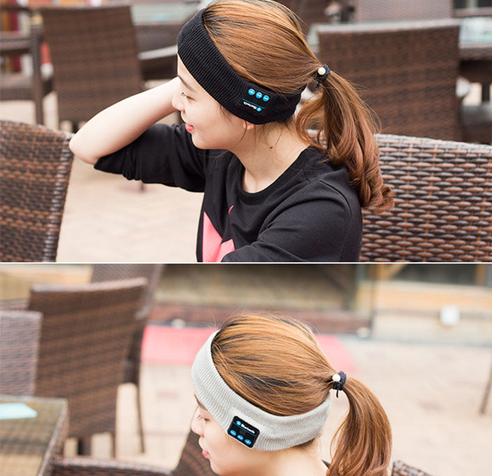 Woman with ponytail wearing a black and a gray Bluetooth headband in a wicker chair.