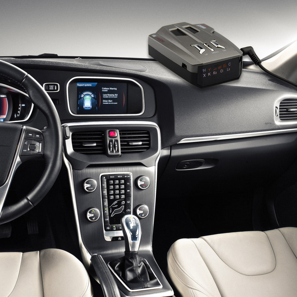 Car interior with beige seats, digital dashboard display, and gadget on dash near gear shift.