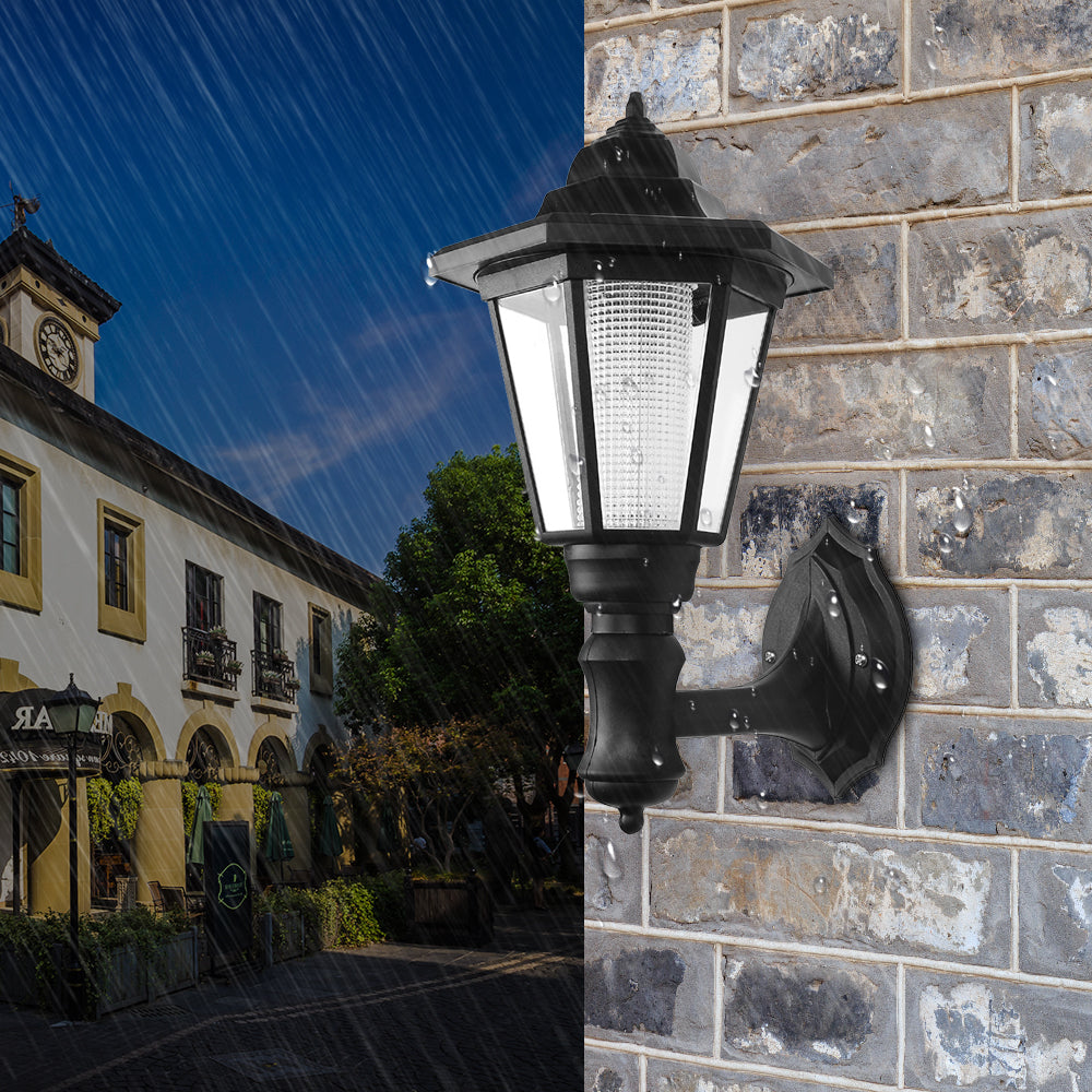 Black wall lantern on wet brick wall with rain, building and tree in the background under blue sky.