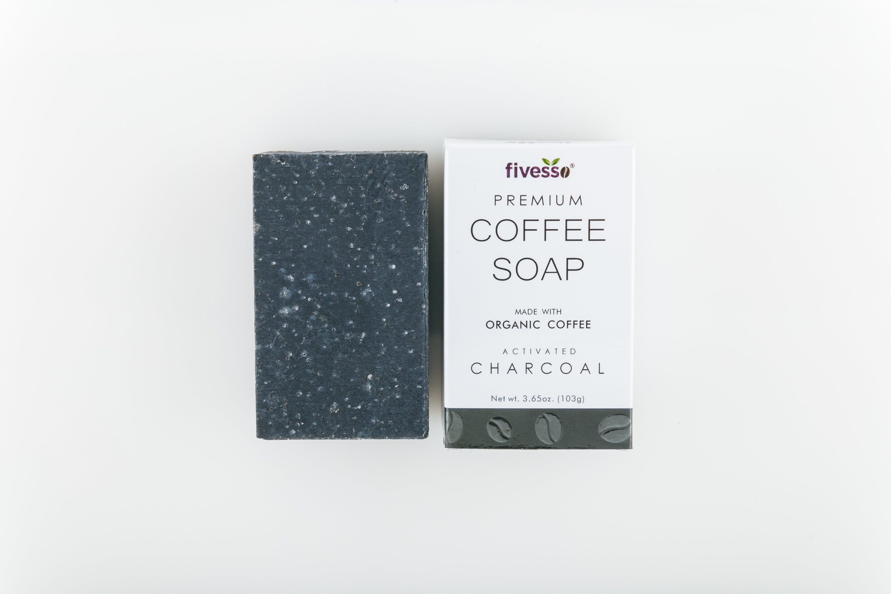 Dark speckled soap bar beside white coffee soap box with text on a light background.