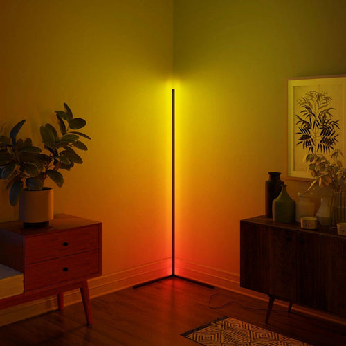 Corner lamp emits yellow-orange glow; mid-century furniture, plant, art, and rug in warm-lit room.