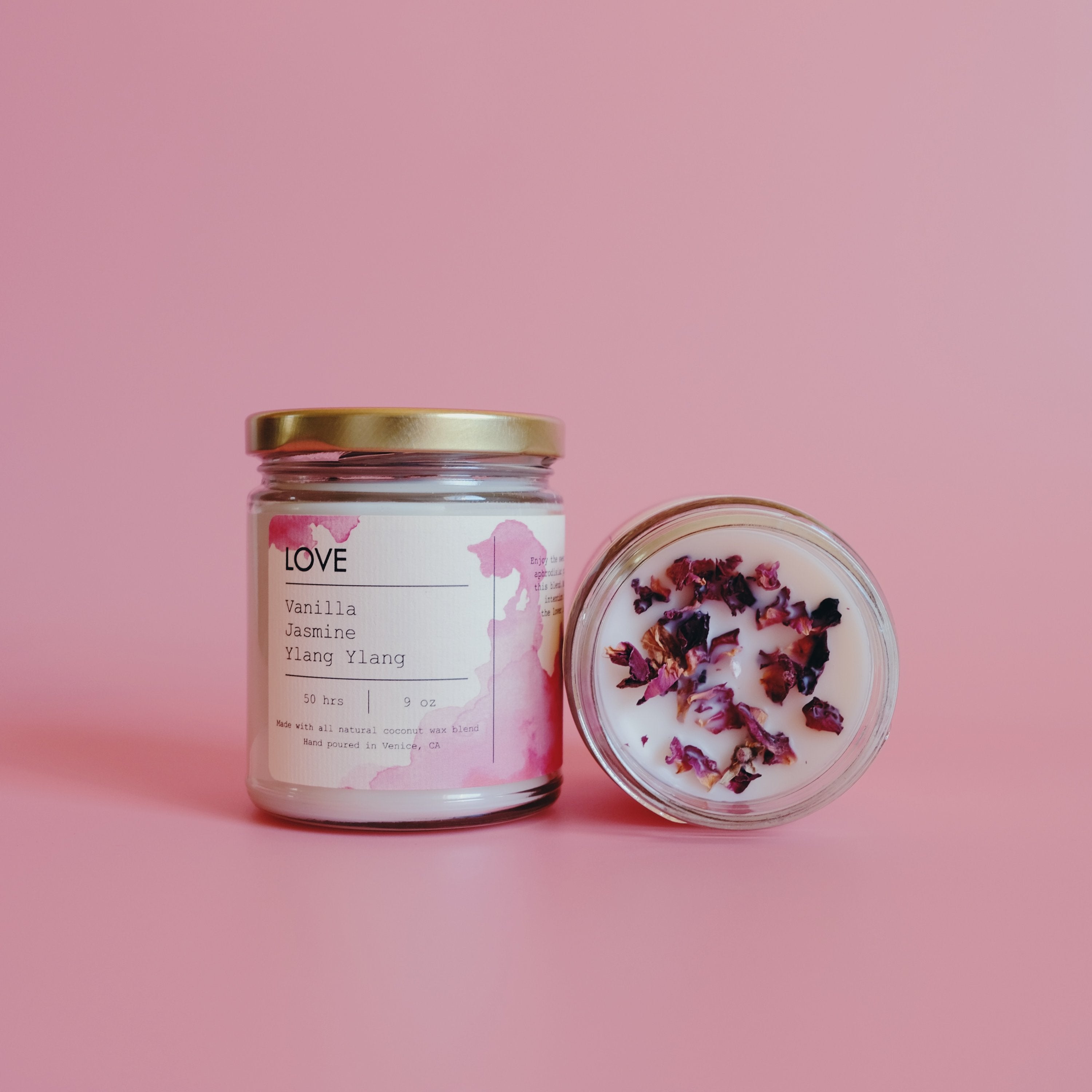 Two jars on pink background; one candle upright, the other open with dried flowers on top.