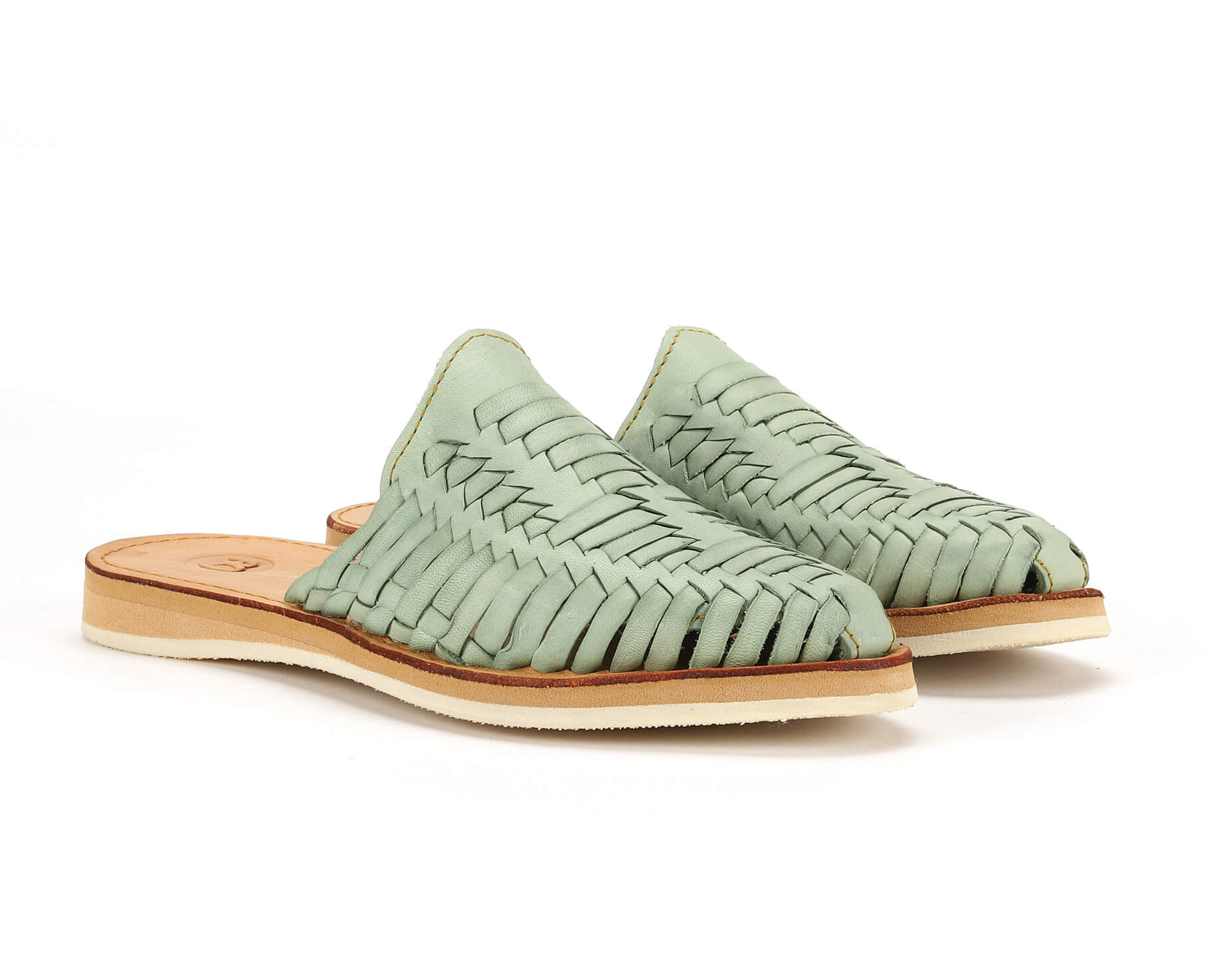 Light green woven leather slip-on sandals with tan soles on a white background.