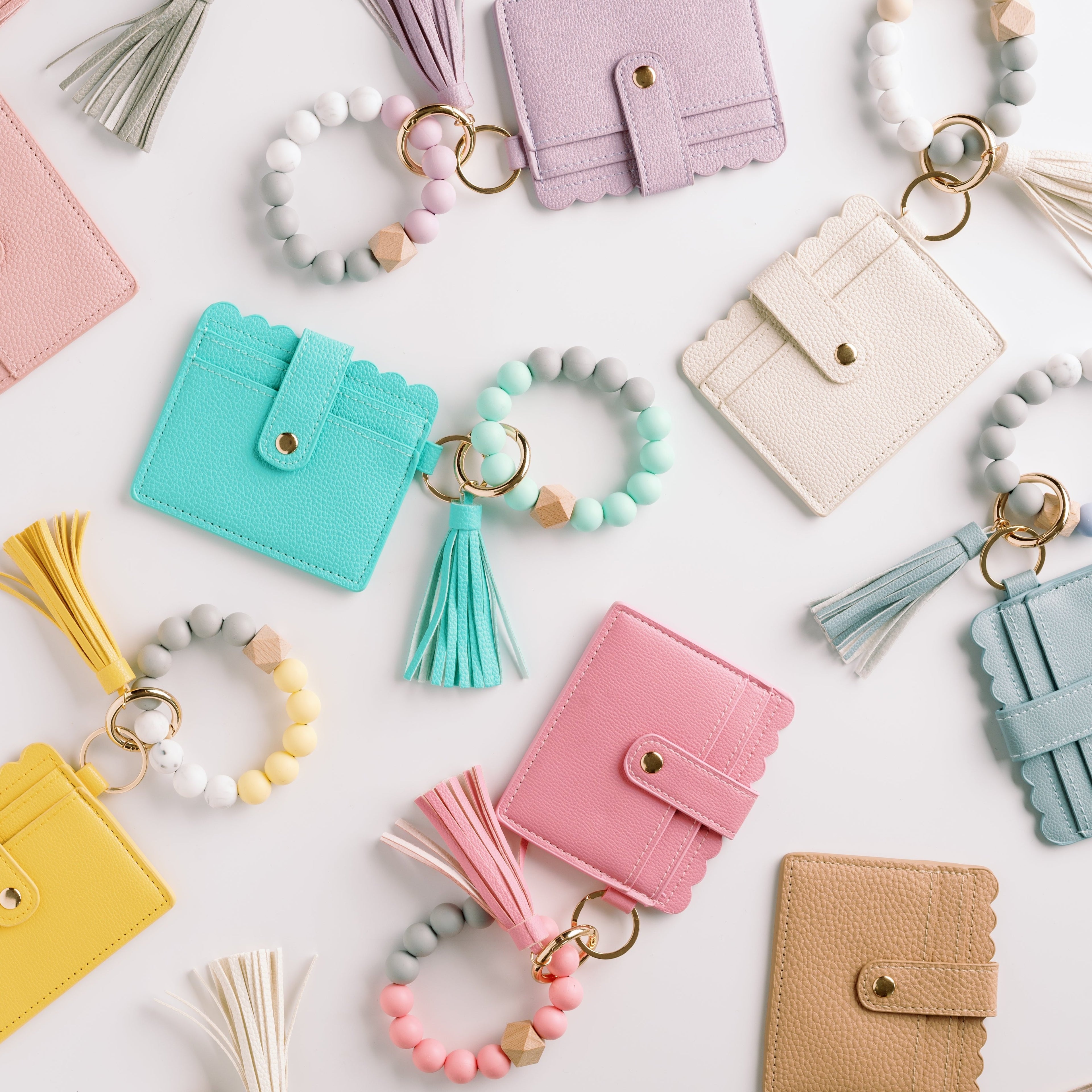 Colorful cardholders with tassels and bead bracelets in pastel shades on a white background.