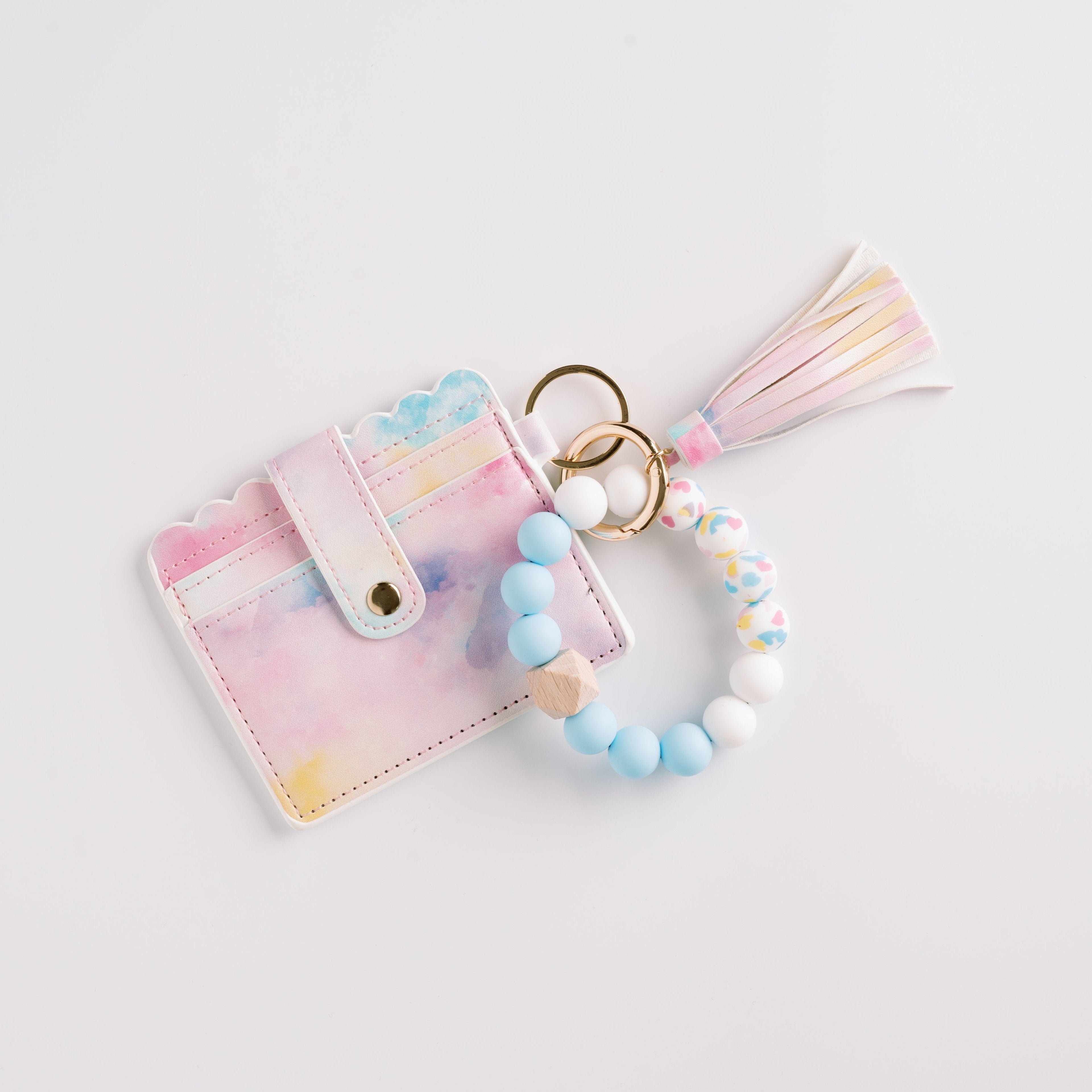 Pastel cardholder with scalloped edges, beaded keychain in blues and whites, and a tassel charm.