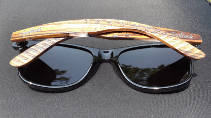 Black sunglasses with wooden, engraved arms on a dark surface.
