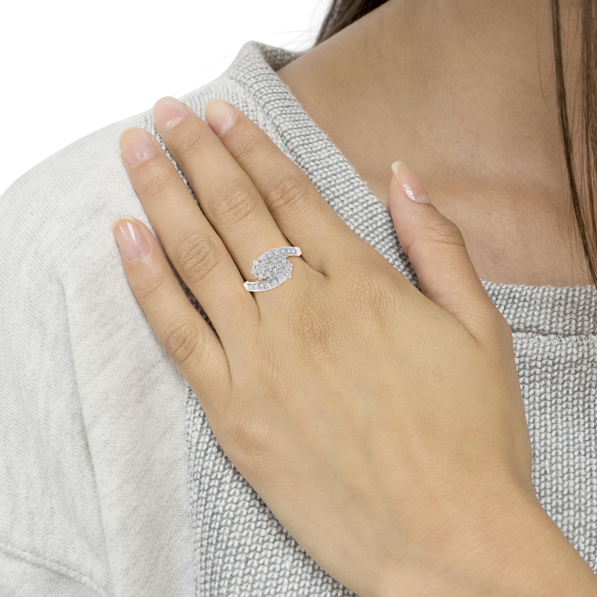 Hand with a silver ring featuring a unique design and small gemstones, against a gray sweater.