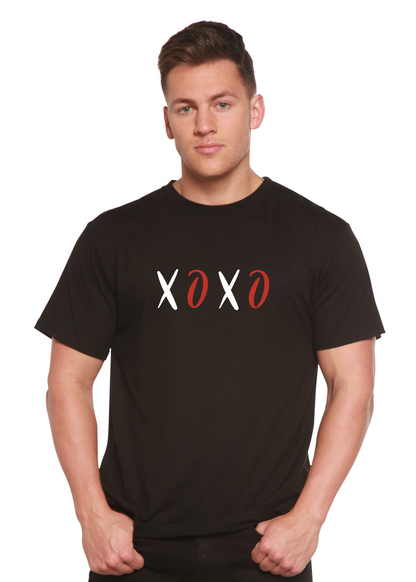 Man in a black shirt with "XOXO" design; letters in white and red. White background.
