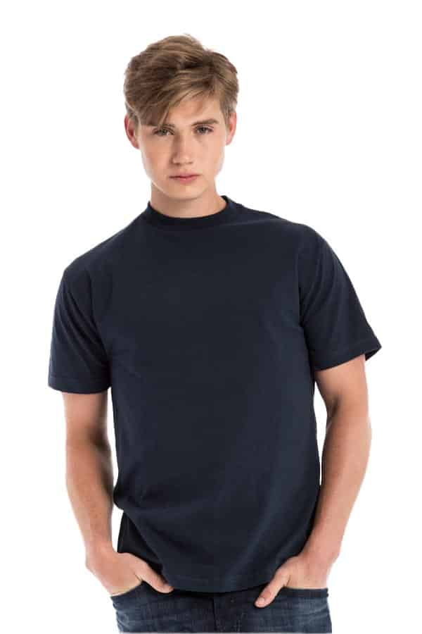 Young man in a plain dark blue t-shirt and jeans, standing with hands in pockets.