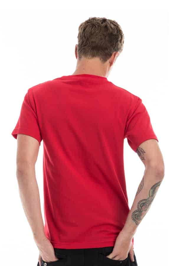 Man in a red t-shirt facing away, with tattooed arm, against a white background.