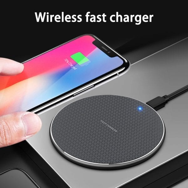 Black wireless charger with textured surface and blue indicator charging a smartphone.