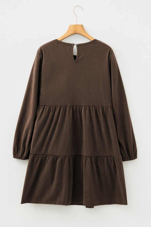 Brown long-sleeve dress with tiered skirt and keyhole detail, hanging on a wooden hanger.