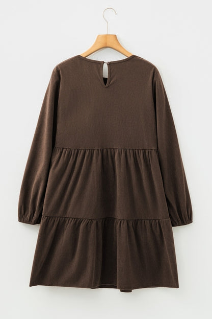 Brown long-sleeve dress with tiered skirt and keyhole detail, hanging on a wooden hanger.