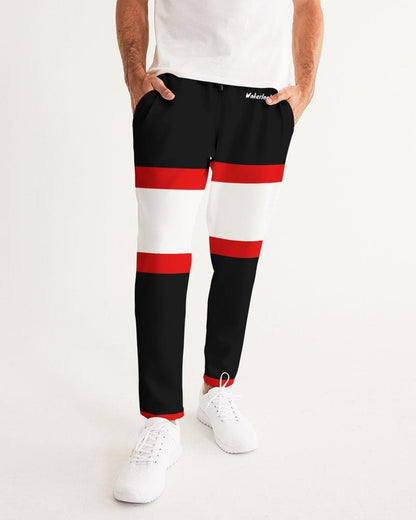 Man wears black pants with red and white stripes and white shoes. White shirt partially visible.