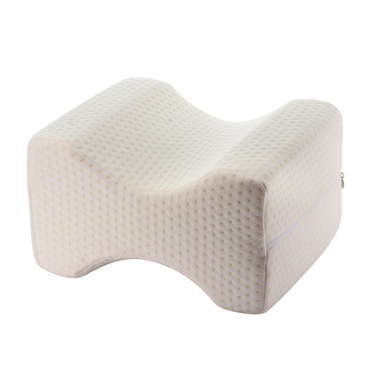 Cream-colored orthopedic knee pillow with a dotted texture and zippered cover.