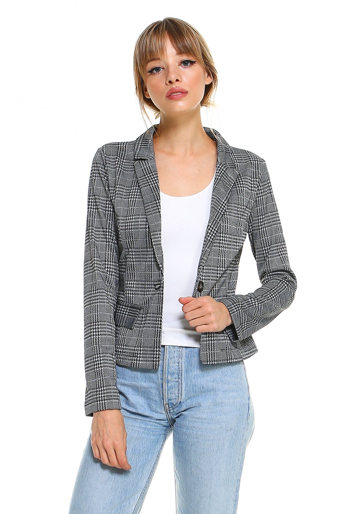 Woman in a plaid gray blazer, white top, and light blue jeans on a white background.