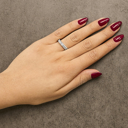 Hand with maroon nails and a silver ring on a textured gray surface.