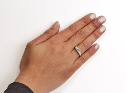 Hand wearing a gold ring with three diamonds, on a white background.
