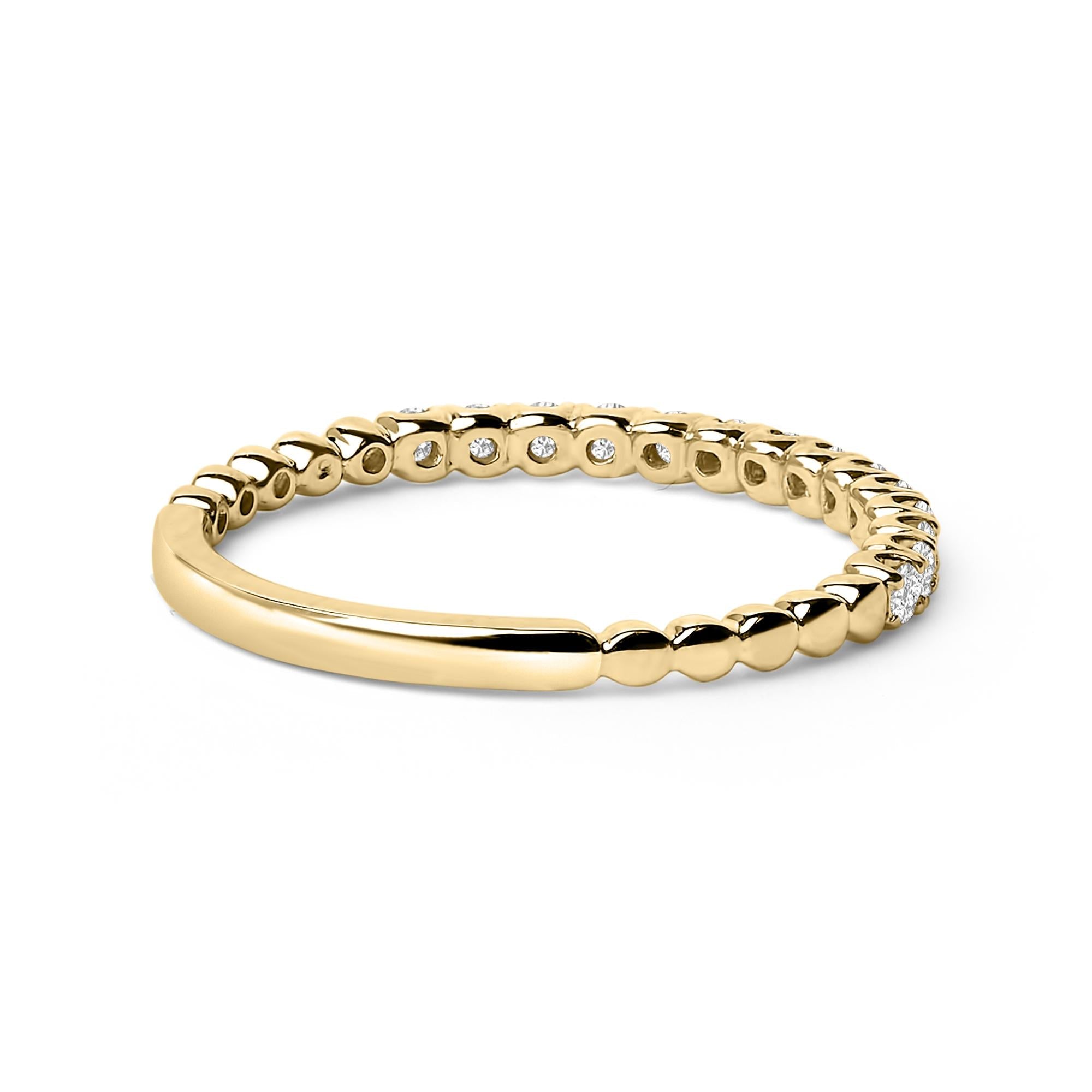 Gold ring with a beaded texture and embedded diamonds, reflecting light on a white background.