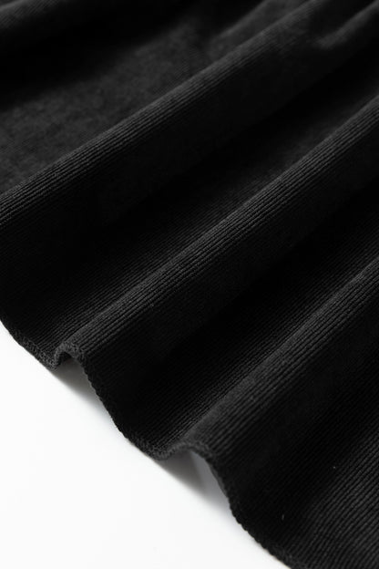 Close-up of black ribbed fabric with wavy folds against a white background.