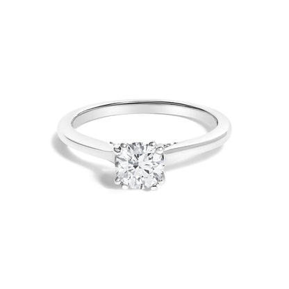 Silver ring with a round, sparkling diamond set in prongs, displayed on a white background.