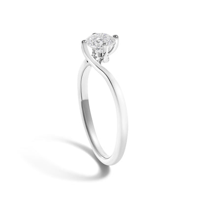 Silver ring with a round diamond set in a twisted prong setting, casting a soft shadow on white.