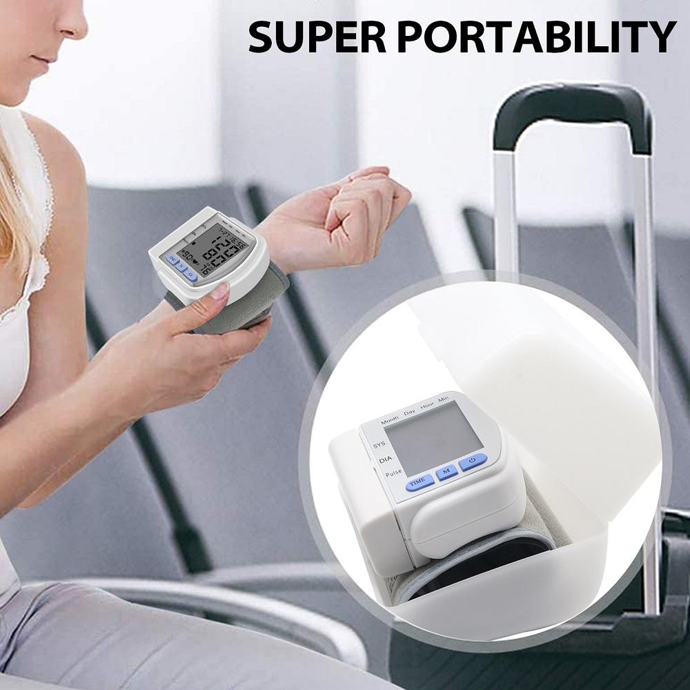 Woman using a portable white blood pressure monitor with a suitcase in the background.