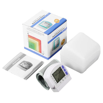 Wrist blood pressure monitor with gray cuff, box, white case, and instruction manual included.